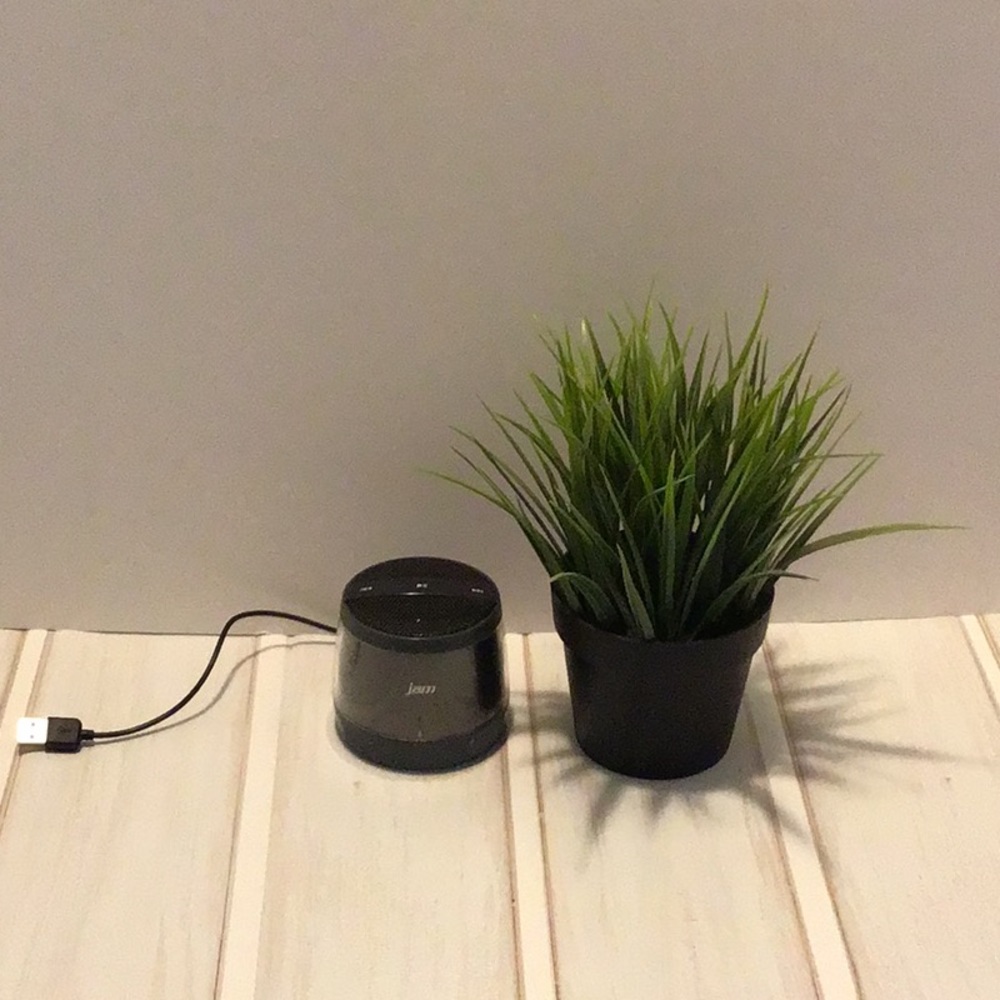 Dark gray/charcoal small wireless portable speaker with charging cable.